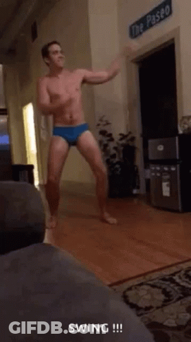 A Shirtless Man In Underwear Is Dancing In A Living Room GIF