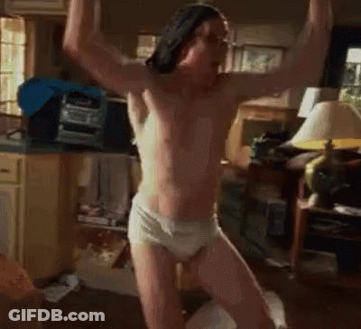 A Shirtless Man In Underwear Is Standing In A Living Room With His Arms In The Air . GIF