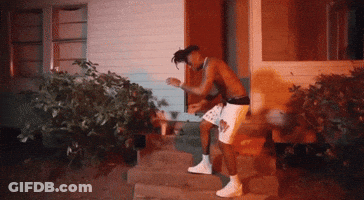 A Shirtless Man In White Shorts Is Standing In Front Of A House GIF