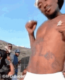 A Shirtless Man In White Underwear Is Dancing In Front Of A Crowd . GIF