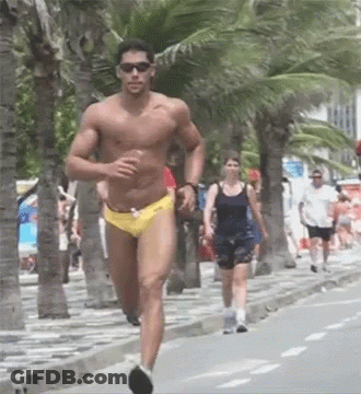 A Shirtless Man In Yellow Swim Trunks Is Running Down A Sidewalk GIF