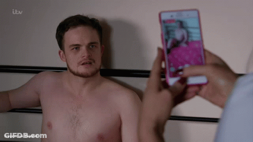A Shirtless Man Is Being Photographed On A Cell Phone By Someone With Itv Written On The Bottom Of The Screen GIF
