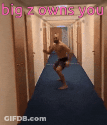 A Shirtless Man Is Dancing In A Hallway With The Words " Big Z Owns You " Above Him GIF