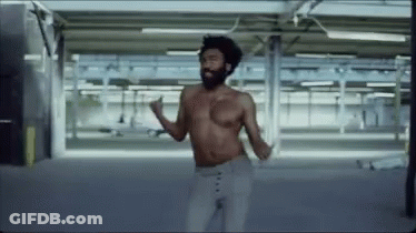 A Shirtless Man Is Dancing In An Empty Parking Garage . GIF