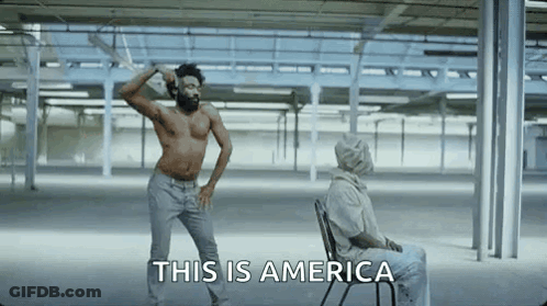 A Shirtless Man Is Dancing In An Empty Room Next To A Man In A Chair . GIF