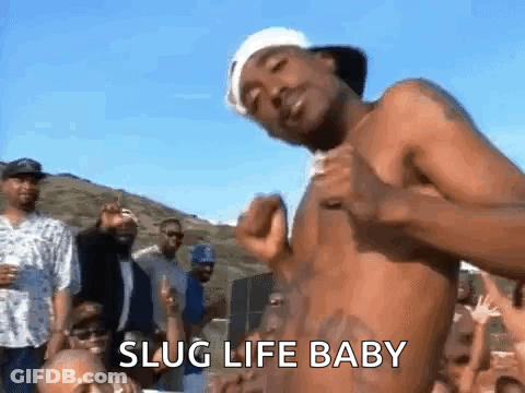 A Shirtless Man Is Dancing In Front Of A Crowd Of People With The Words `` Slug Life Baby '' Written On The Bottom . GIF