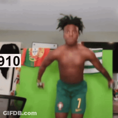 A Shirtless Man Is Dancing In Front Of A Green Screen With The Number 910 On It GIF
