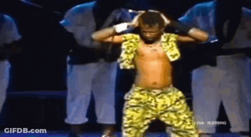 A Shirtless Man Is Dancing On A Stage With A Group Of Men Behind Him . GIF