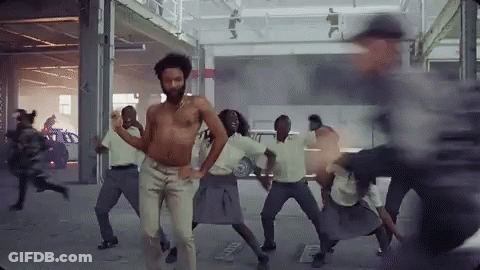 A Shirtless Man Is Dancing With A Group Of People . GIF