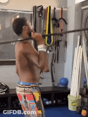 A Shirtless Man Is Doing A Pull Up In A Gym GIF