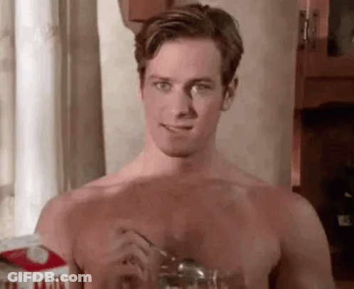 A Shirtless Man Is Eating A Glass Of Milk With A Spoon From A Carton Of Milk . GIF