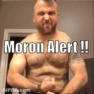 A Shirtless Man Is Flexing His Muscles With The Words Moron Alert Written On His Chest . GIF