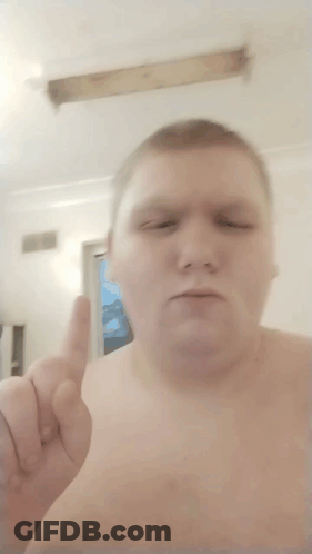 A Shirtless Man Is Giving A Thumbs Up In Front Of A Window GIF