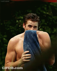 A Shirtless Man Is Holding A Blue Towel Over His Mouth GIF