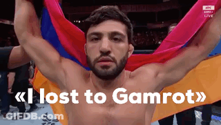 A Shirtless Man Is Holding A Colorful Flag And The Words Lost To Gamrot Are Above Him GIF