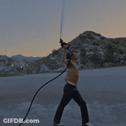 A Shirtless Man Is Holding A Hose In His Hand GIF