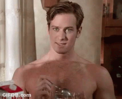 A Shirtless Man Is Holding A Spoon In His Hand And Drinking Milk From A Glass . GIF