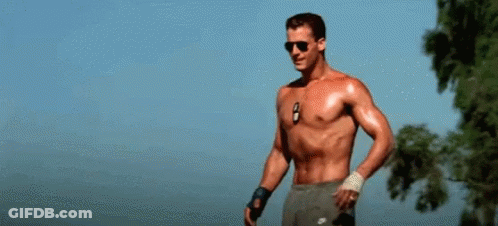 A Shirtless Man Is Holding A Volleyball In His Hand . GIF