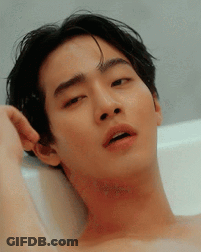 A Shirtless Man Is Laying In A Bathtub With His Mouth Open GIF
