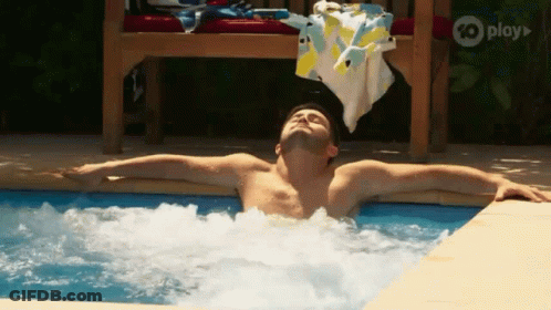A Shirtless Man Is Laying In A Jacuzzi Pool With His Arms Outstretched . GIF