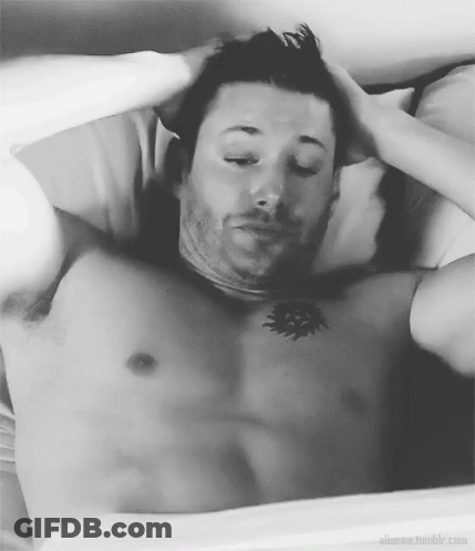 A Shirtless Man Is Laying In Bed With His Eyes Closed And His Hands On His Head . GIF