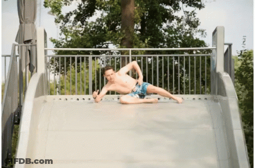 A Shirtless Man Is Laying On A Slide And Giving The Thumbs Up GIF