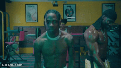 A Shirtless Man Is Lifting Weights In A Gym With Other Men GIF