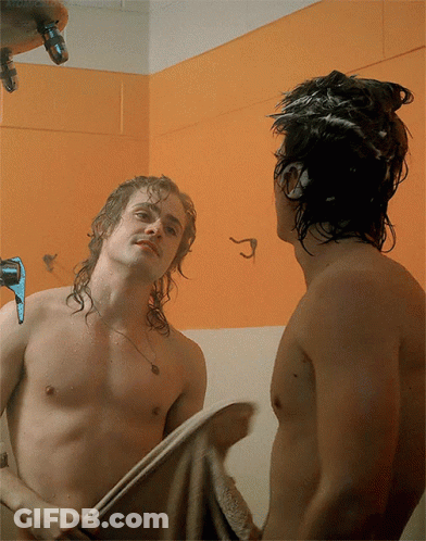 A Shirtless Man Is Looking At His Reflection In A Mirror GIF