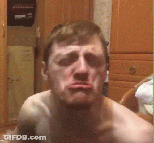 A Shirtless Man Is Making A Funny Face While Sitting On A Chair In A Room . GIF
