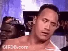 A Shirtless Man Is Making A Funny Face While Standing In A Room . GIF