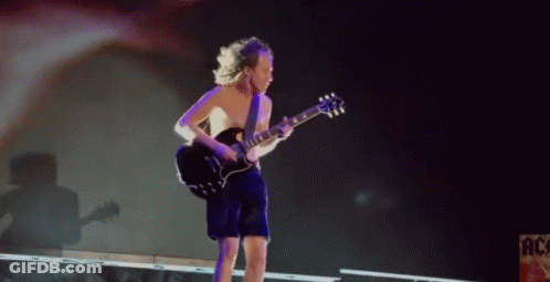 A Shirtless Man Is Playing A Guitar On Stage In Front Of A Sign That Says Ac GIF