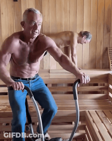 A Shirtless Man Is Riding An Exercise Bike In A Wooden Sauna GIF
