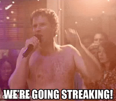 A Shirtless Man Is Singing Into A Microphone In Front Of A Crowd At A Party . GIF