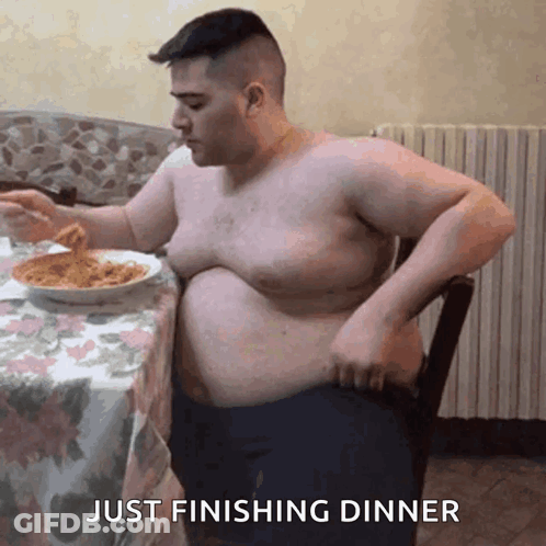 A Shirtless Man Is Sitting At A Table With A Bowl Of Spaghetti And The Words Just Finishing Dinner Below Him GIF