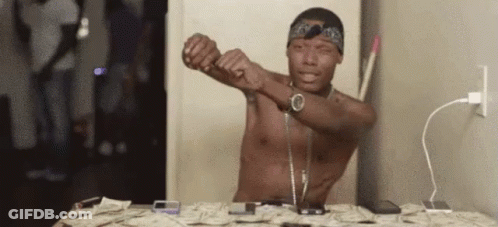 A Shirtless Man Is Sitting At A Table With A Bunch Of Money . GIF