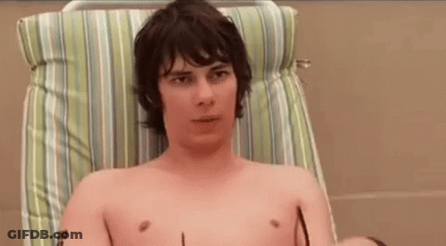 A Shirtless Man Is Sitting In A Chair With Sunglasses On . GIF