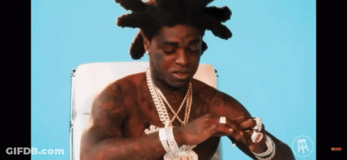 A Shirtless Man Is Sitting In A Chair With The Letter A On The Bottom GIF