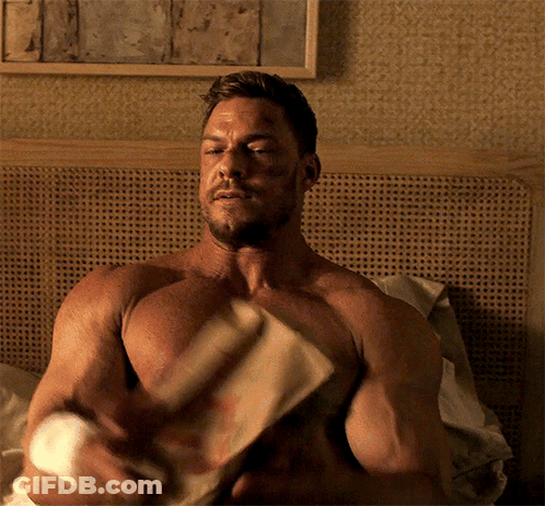 A Shirtless Man Is Sitting On A Bed With His Eyes Closed GIF
