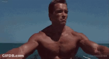 A Shirtless Man Is Sitting On A Boat In The Ocean . GIF