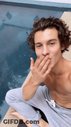 A Shirtless Man Is Sitting On The Edge Of A Pool Covering His Mouth With His Hand . GIF