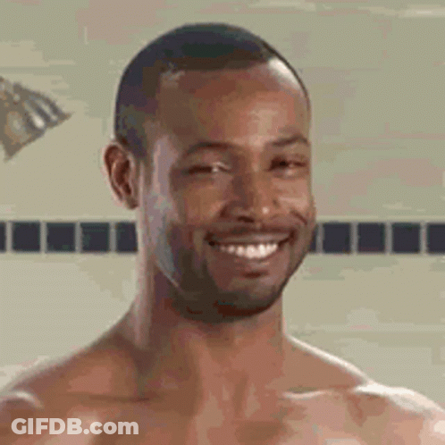 A Shirtless Man Is Smiling While Taking A Shower . GIF