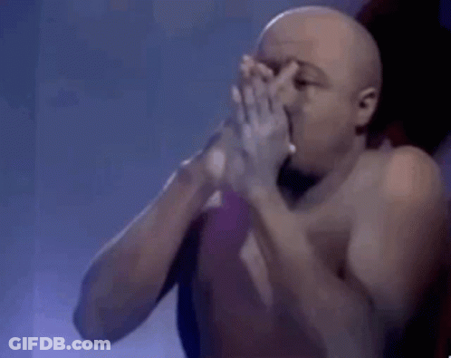 A Shirtless Man Is Smoking A Cigarette And Blowing Smoke Into His Mouth . GIF