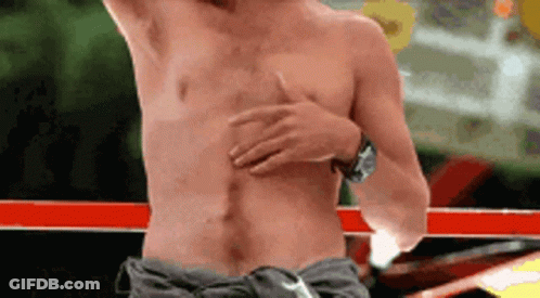 A Shirtless Man Is Standing In A Boxing Ring With His Hand On His Chest . GIF