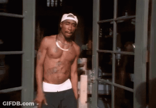 A Shirtless Man Is Standing In A Doorway Wearing A White Hat GIF