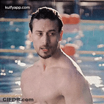 A Shirtless Man Is Standing In A Pool . GIF