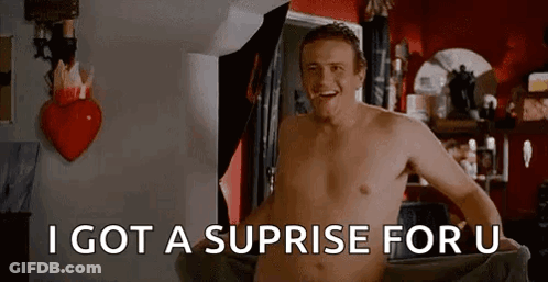 A Shirtless Man Is Standing In A Room With A Heart On The Wall . GIF