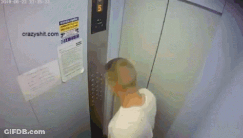 A Shirtless Man Is Standing In An Elevator With A Sign That Says Crazyshit.com On It GIF