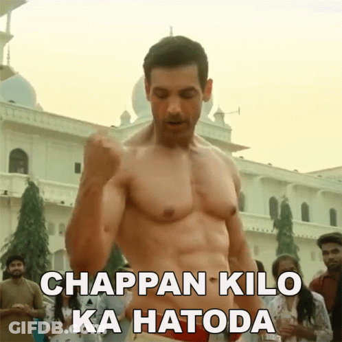 A Shirtless Man Is Standing In Front Of A Building With The Words Chappan Kilo Ka Hatoda Above Him GIF