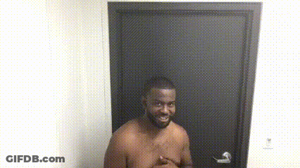A Shirtless Man Is Standing In Front Of A Door With His Hands On His Chest . GIF