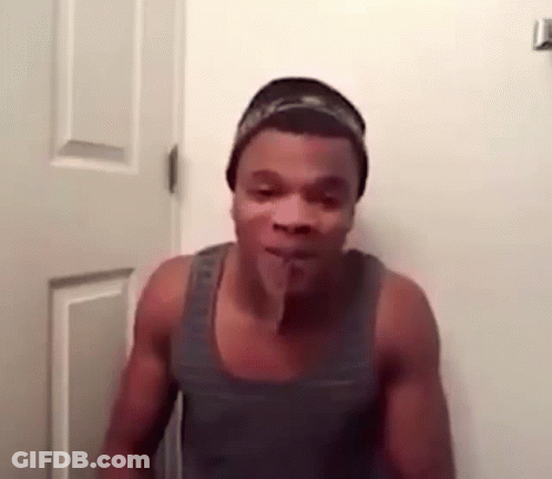 A Shirtless Man Is Standing In Front Of A Door With His Tongue Sticking Out . GIF
